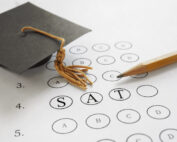 SAT test with pencil and mortar board graduation cap